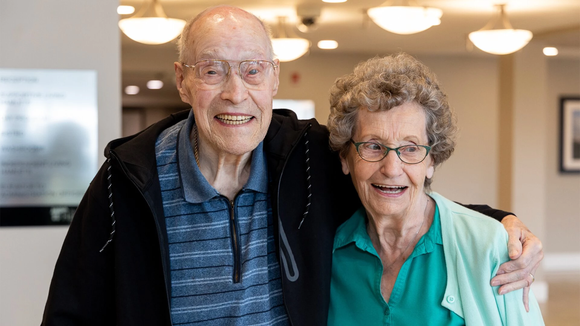 An elderly couple is happy and hugging one other.
