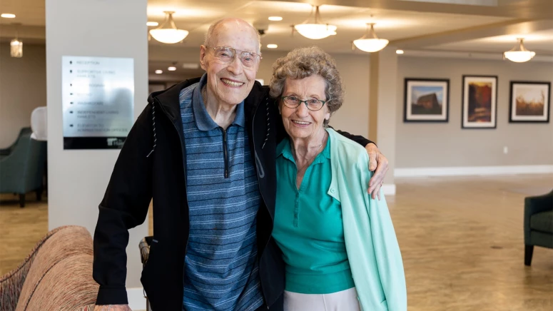 An elderly couple standing and hugging each other at the Hamlets red deer residence