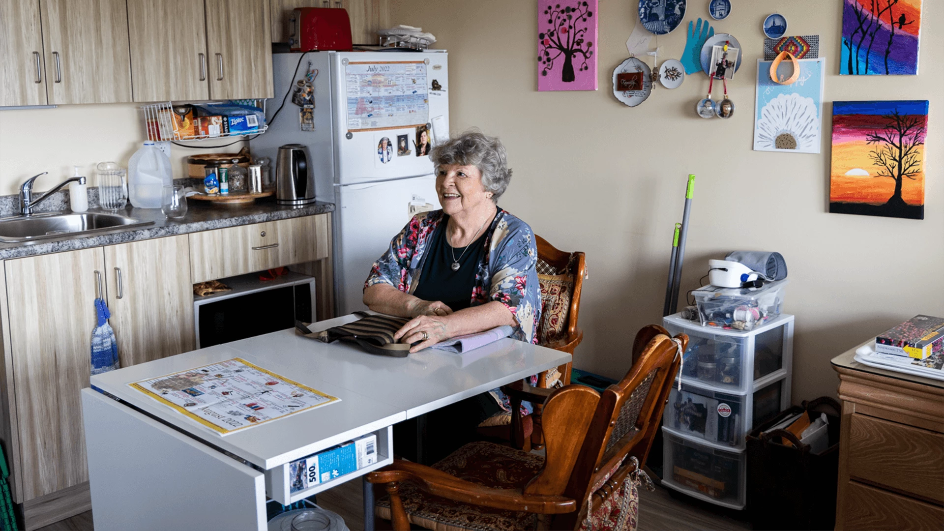 An elderly lady sitting on a dining table in her room
