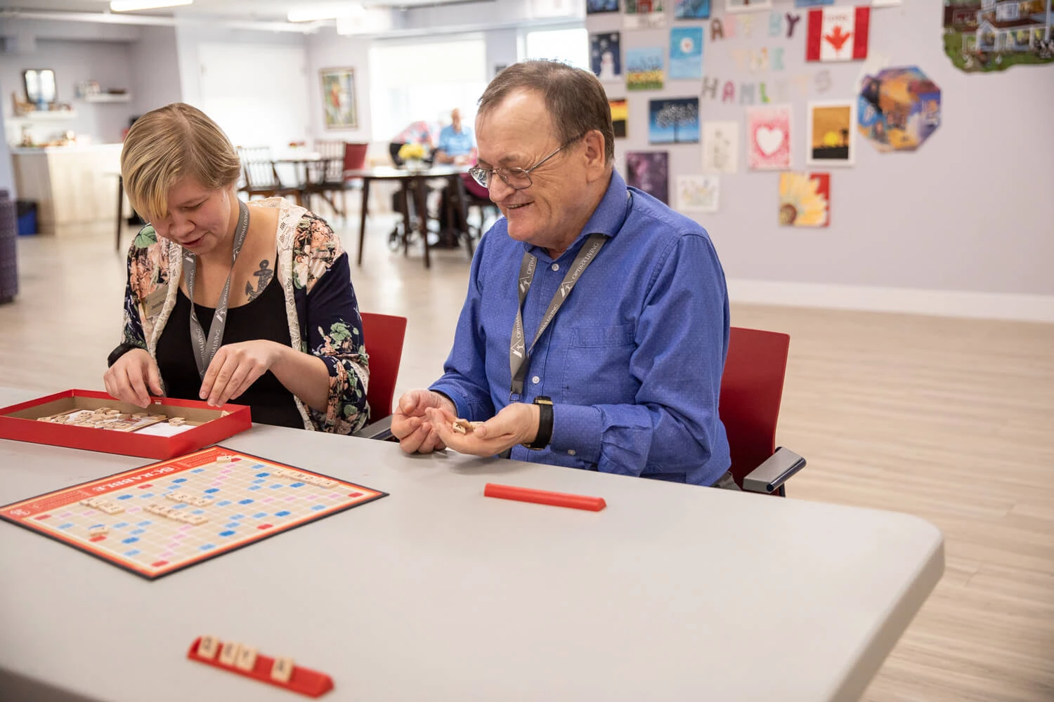 Two people sitting at a table playing a game of scrabble.