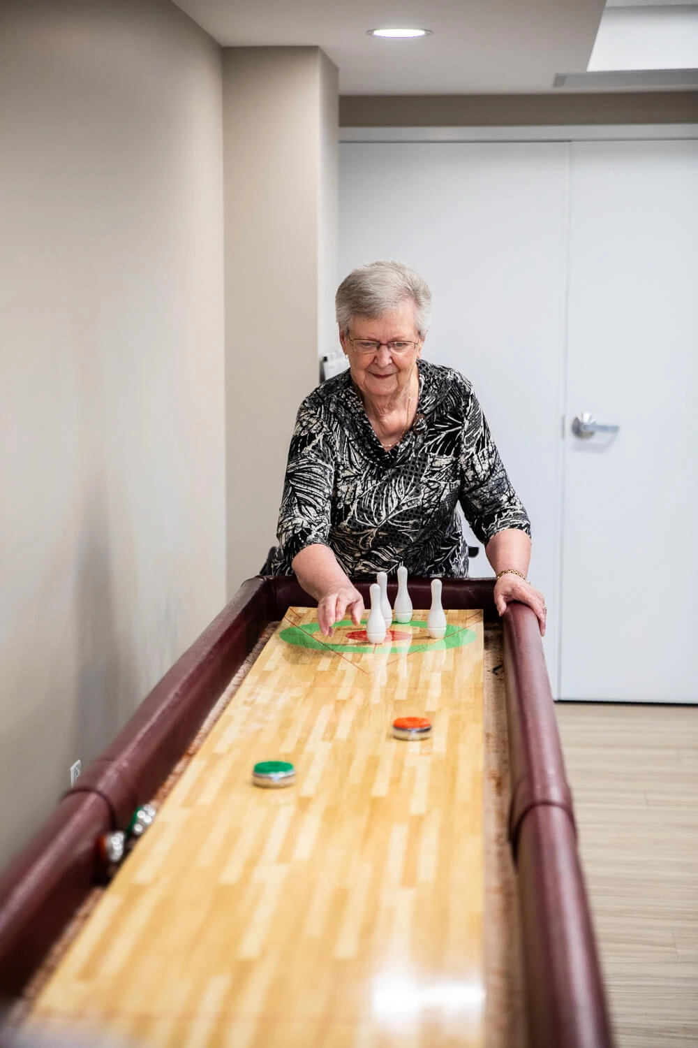 An older woman playing shuffleboard.